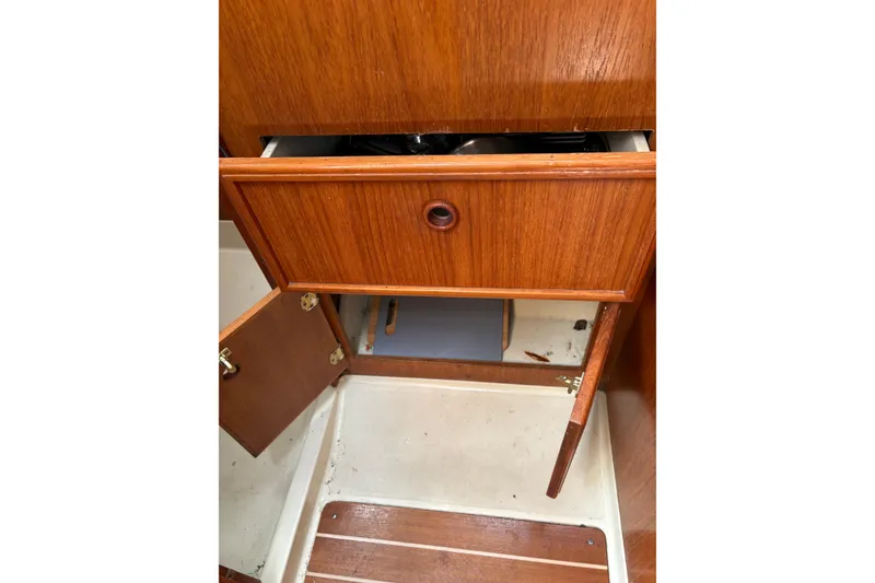 Slide: The Image of Wooden cabinetry inside a 1988 Pearson 28 sailboat, featuring open drawers and doors. - 24