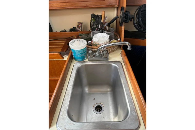 Slide: The Image of Galley sink in a 1988 Pearson 28 sailboat with utensils and cleaning supplies. - 26