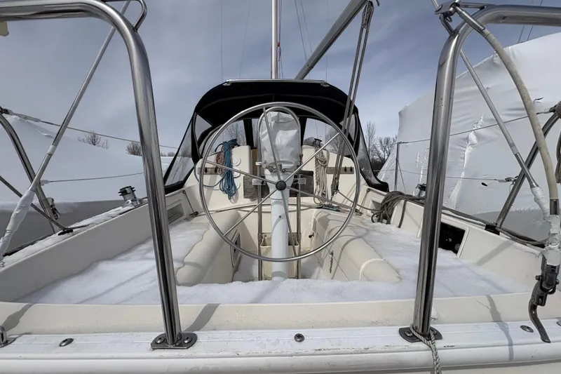 Slide: The Image of Sailboat cockpit of a 1988 Pearson 28, covered in snow, with a steering wheel. - 6