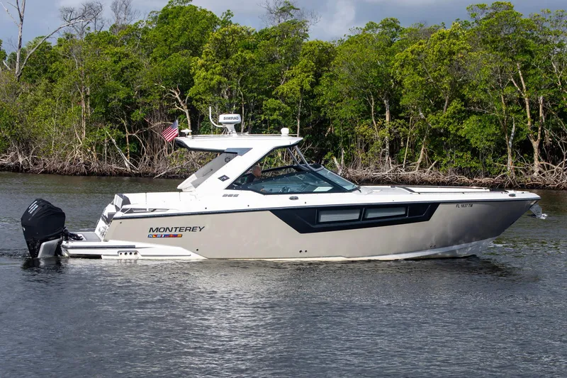 Slide: The Image of 2022 Monterey 385SS Super Sport boat cruising on a calm river with lush greenery. - 4