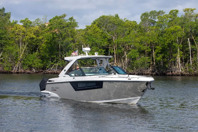 Slide: The Image of 2022 Monterey 385SS Super Sport boat cruising on a calm river with lush greenery. - 5