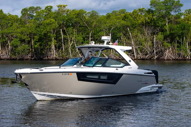 Slide: The Image of 2022 Monterey 385SS Super Sport boat cruising on a calm river with lush greenery. - 6