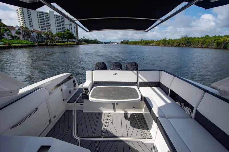 Slide: The Image of 2022 Monterey 385SS Super Sport boat interior with seating, table, and waterfront view. - 8
