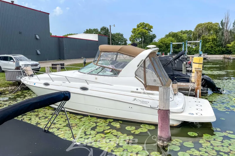 Slide: The Image of 1998 Cruisers Yachts 2870 Rogue docked by a serene lakeside with lily pads. - 5