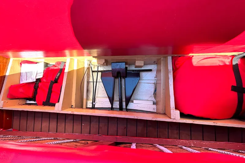 Slide: The Image of Storage compartments in a 1956 Chris-Craft Capri 21 boat, containing red life jackets and equipment. - 17
