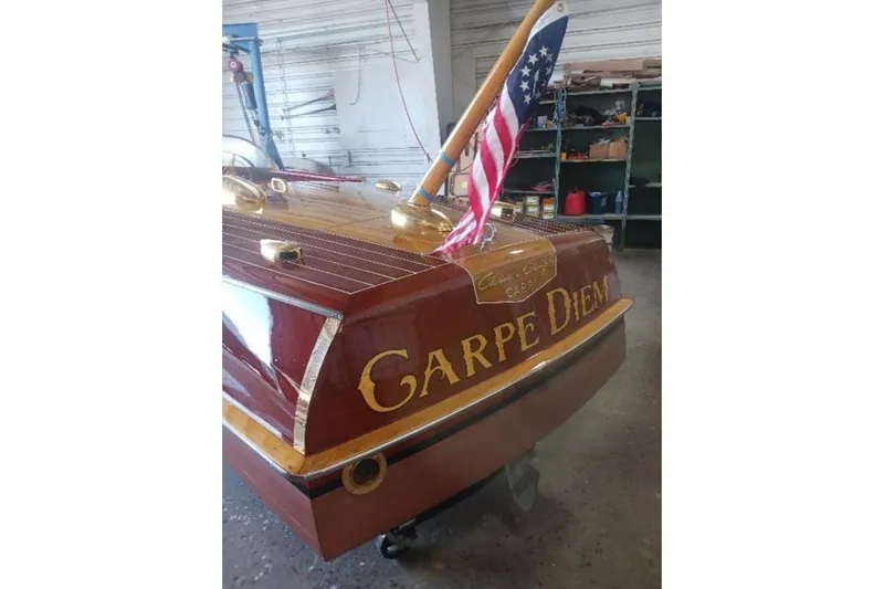 Slide: The Image of 1956 Chris-Craft Capri 21 boat with "Carpe Diem" lettering and American flag in a workshop. - 5