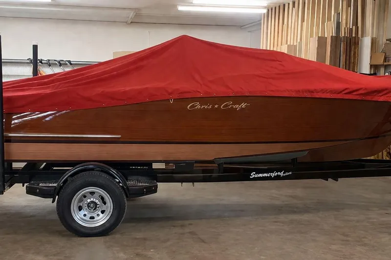 Slide: The Image of 1956 Chris-Craft Capri 21 boat with red cover on trailer in a workshop. - 9