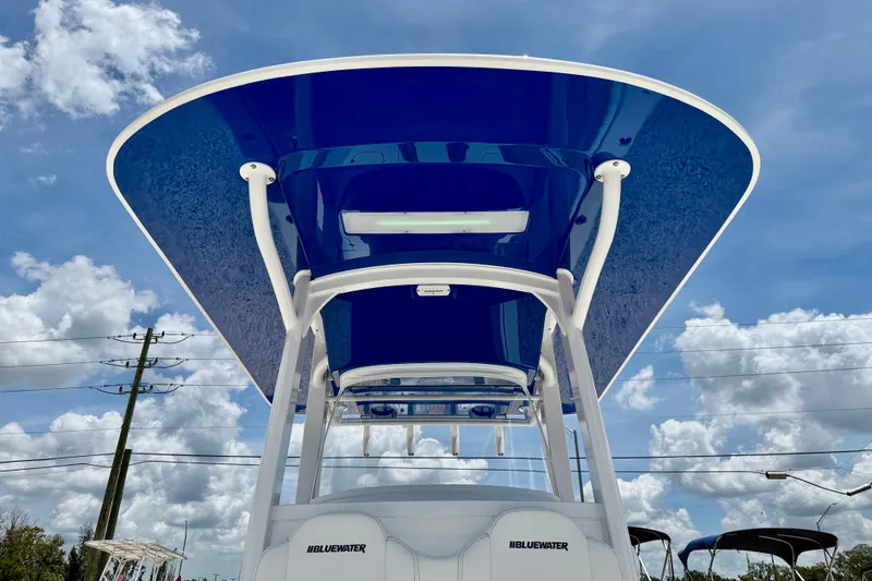 Slide: The Image of Bluewater 25t boat, 2025 model, featuring a sleek blue canopy against a cloudy sky. - 43