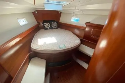 Slide: The Image of 2003 Beneteau 423 yacht cabin with cozy bed, wooden interior, and natural light. - 16