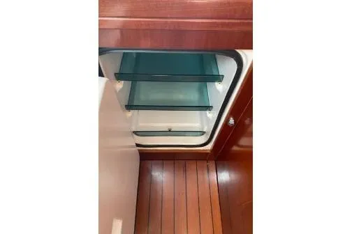 Slide: The Image of Open refrigerator in 2003 Beneteau 423 yacht, featuring wooden interior and glass shelves. - 19