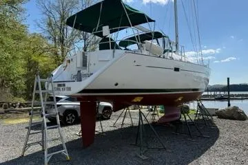 Slide: The Image of 2003 Beneteau 423 sailboat on stands, with green canopy, near a waterfront. - 4
