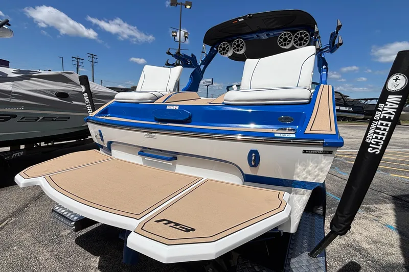 Slide: The Image of 2026 MB B52 23 Alpha boat with blue and white design, docked outdoors. - 11
