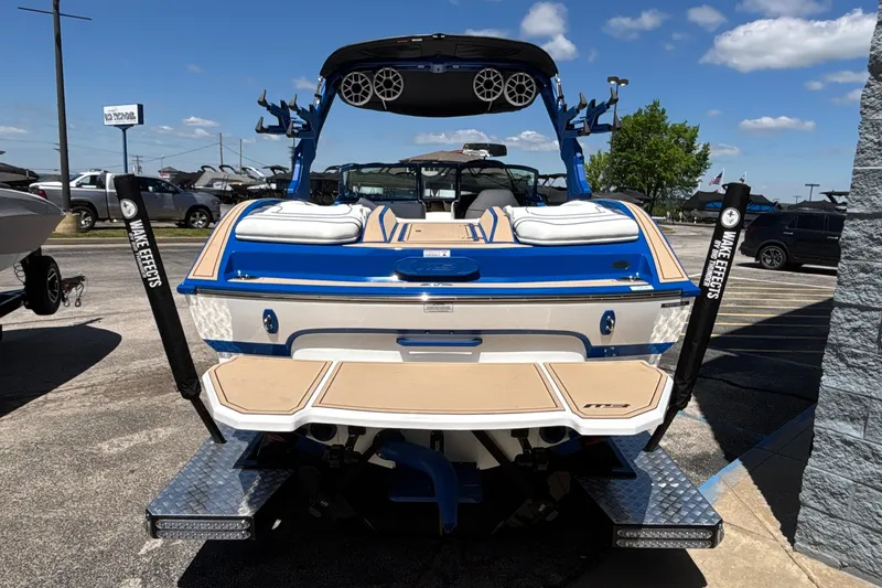 Slide: The Image of 2026 MB B52 23 Alpha boat, blue and white, parked outdoors under a clear sky. - 6