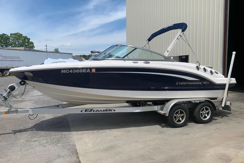 The Image of 2014 Chaparral 206 SSi boat on EZ Loader trailer, parked outside a building. - 1