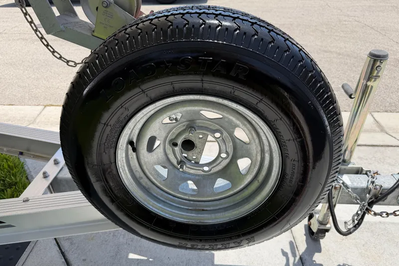 Slide: The Image of Trailer tire on a Carolina Skiff 21 LS, 2023 model, parked on pavement. - 23