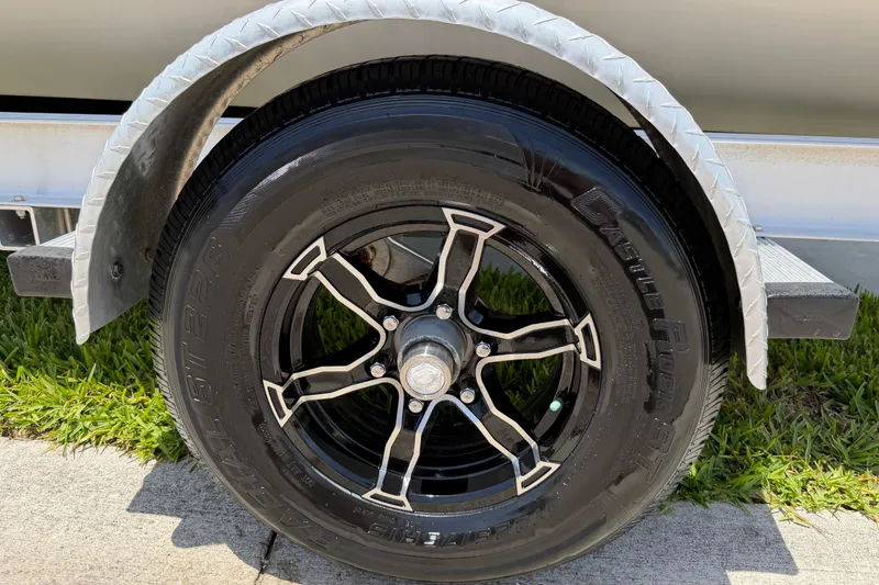 Slide: The Image of Trailer wheel of 2023 Carolina Skiff 21 LS boat on grass and pavement. - 29