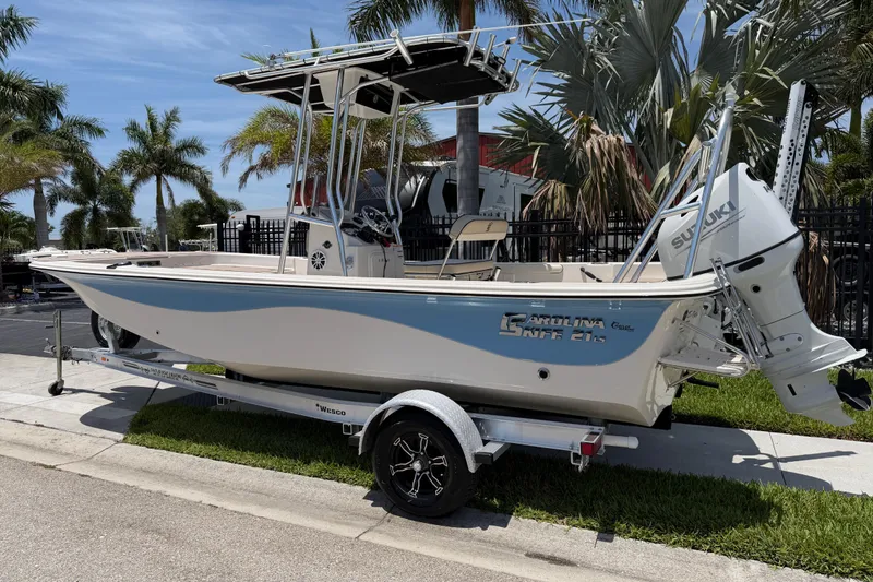 Slide: The Image of 2023 Carolina Skiff 21 LS boat on trailer, parked near palm trees. - 3