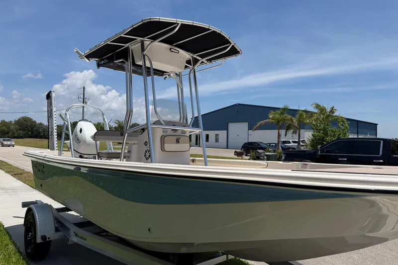 Slide: The Image of 2023 Carolina Skiff 21 LS boat with T-top, parked on a trailer under a clear blue sky. - 34