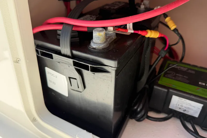 Slide: The Image of Battery compartment of a 2023 Carolina Skiff 21 LS with red cables connected. - 84