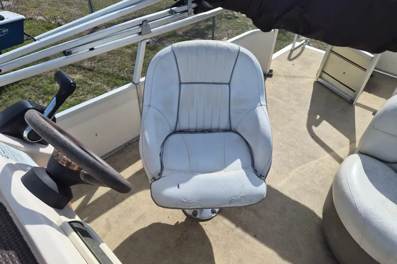 Slide: The Image of 2004 Sun Tracker Fishin' Barge 20 DLX boat interior with worn captain's chair and steering wheel. - 9