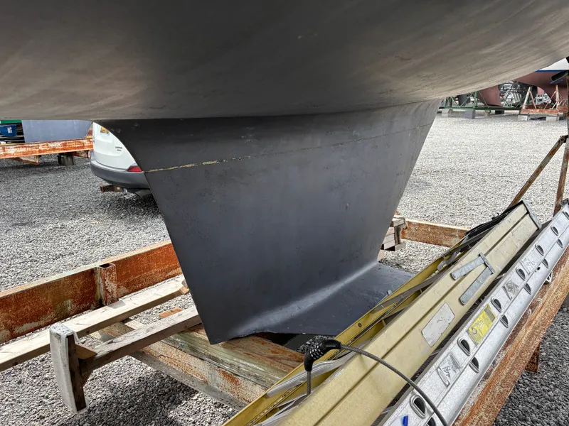 Slide: The Image of Rudder of a 1988 Ericson 34-2 sailboat on a gravel lot. - 11