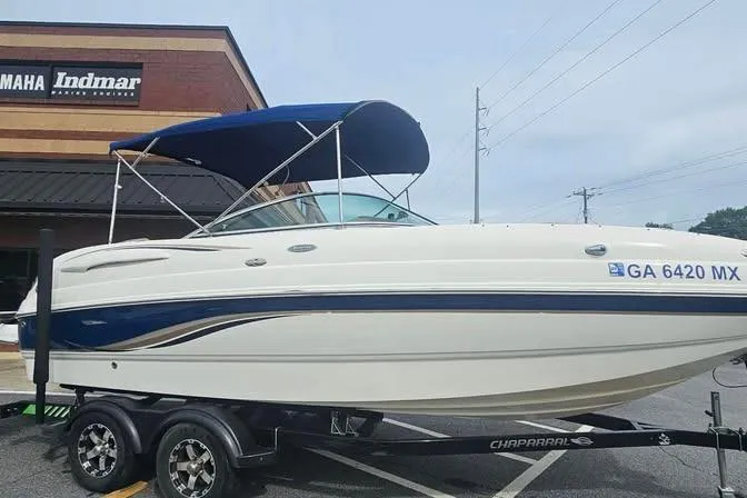 Slide: The Image of 2003 Chaparral Sunesta 236 boat with blue canopy on trailer, parked outside dealership. - 4