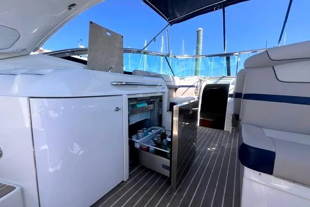 Slide: The Image of 2015 Formula 350 Sun Sport yacht interior with open mini-fridge, sleek seating, and blue canopy. - 6