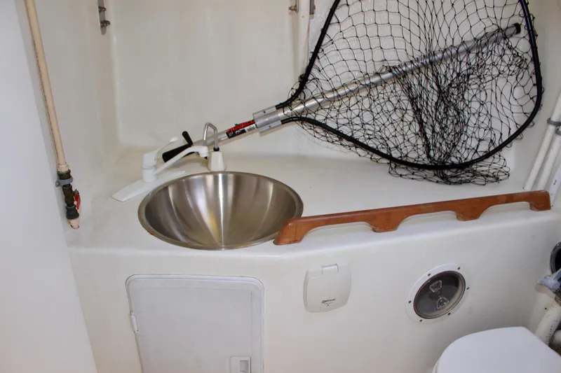 Slide: The Image of Compact boat bathroom with stainless steel sink, fishing net, and wooden rail on a 1993 Freya 39. - 54