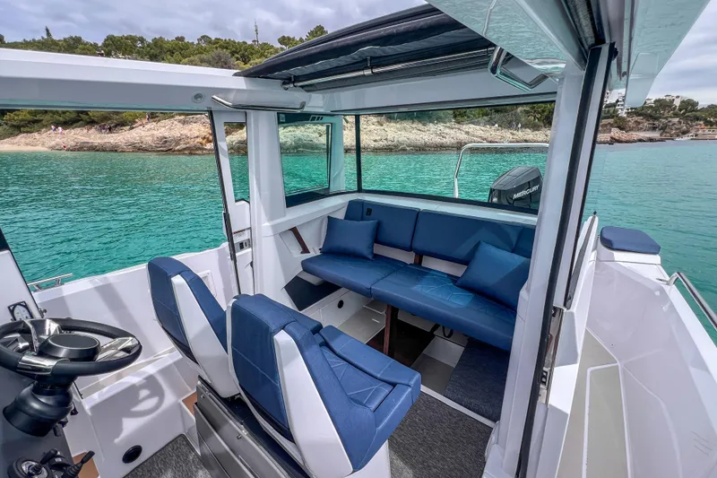 Slide: The Image of 2026 Axopar 29 XC Cross Cabin interior with blue seating, overlooking turquoise waters. - 13