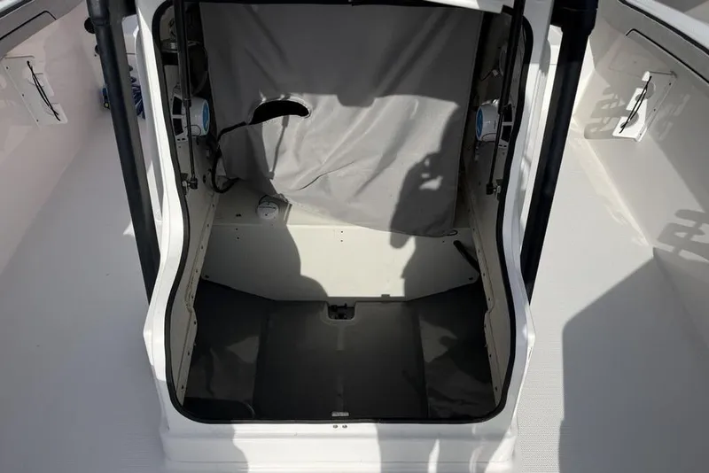 Slide: The Image of 2020 Yamaha Boats 210 FSH Sport interior storage compartment with gray cover. - 12