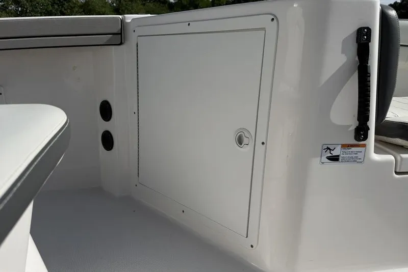 Slide: The Image of 2020 Yamaha Boats 210 FSH Sport interior storage compartment with safety handle and warning label. - 15