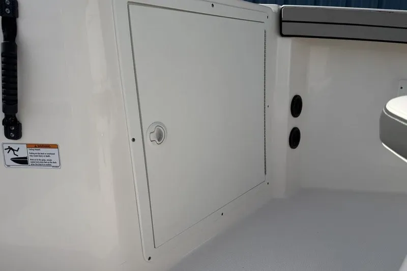 Slide: The Image of 2020 Yamaha Boats 210 FSH Sport interior storage compartment with safety warning label. - 22