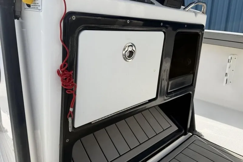 Slide: The Image of 2020 Yamaha Boats 210 FSH Sport interior storage compartment with red safety cord. - 24