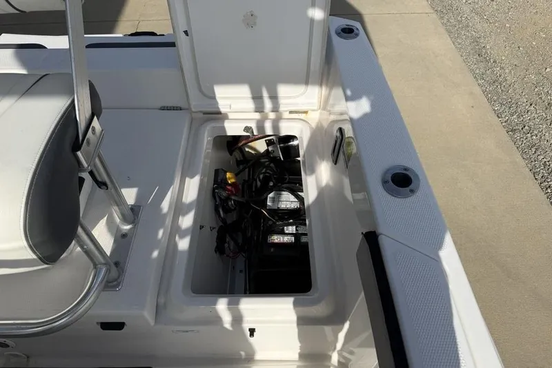 Slide: The Image of 2020 Yamaha Boats 210 FSH Sport storage compartment with visible battery and wiring. - 26