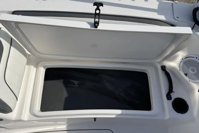 Slide: The Image of Open storage compartment on a 2020 Yamaha Boats 210 FSH Sport, featuring a sleek white interior. - 30