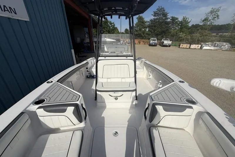 Slide: The Image of 2020 Yamaha Boats 210 FSH Sport interior with seating and storage, parked outdoors. - 40