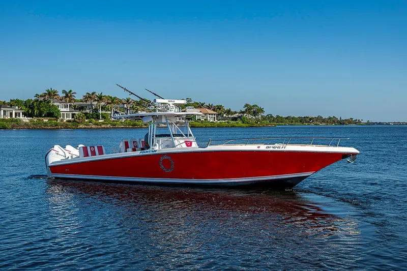 The Image of 2009 Fountain 38 Center Console boat with red hull on calm water, scenic background. - 0