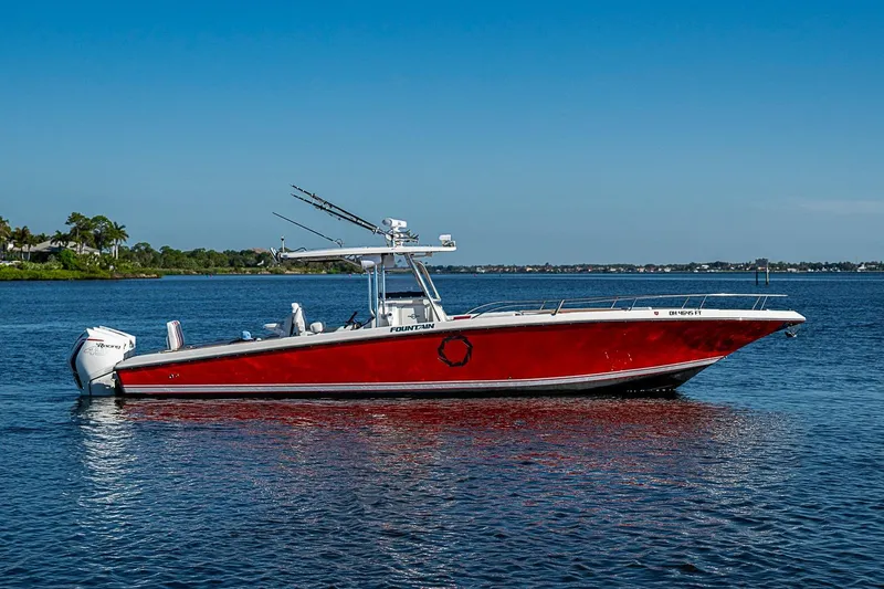 Slide: The Image of 2009 Fountain 38 Center Console boat on calm water, vibrant red hull, clear blue sky. - 2