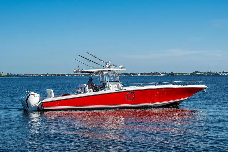 Slide: The Image of 2009 Fountain 38 Center Console boat with red hull on calm water. - 33