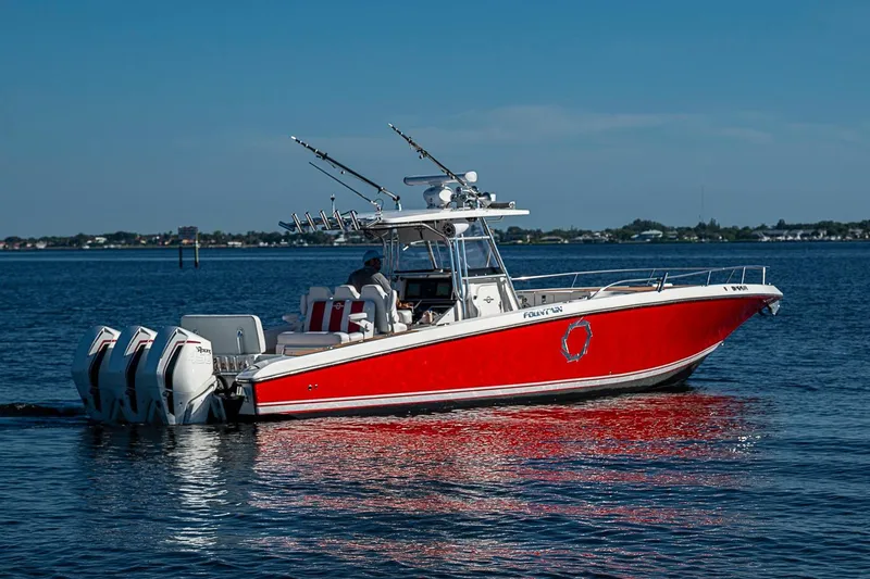 Slide: The Image of 2009 Fountain 38 Center Console boat with red hull on calm water. - 34