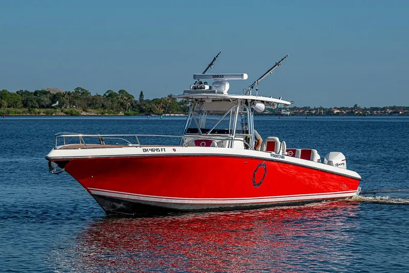 Slide: The Image of 2009 Fountain 38 Center Console boat with red hull cruising on a calm lake. - 38