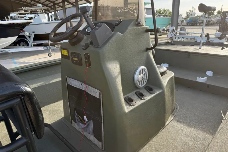 Slide: The Image of 2014 Excel 203 Bay Pro boat console with steering wheel and controls in a marina setting. - 12