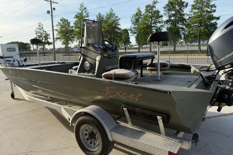 Slide: The Image of 2014 Excel 203 Bay Pro boat on trailer, featuring seating and motor, parked outdoors. - 6