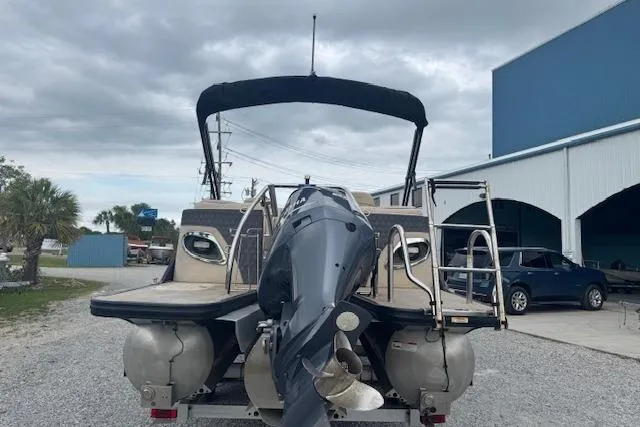 Slide: The Image of 2020 Barletta Lusso 25QCSS pontoon boat with outboard motor, parked outdoors. - 6