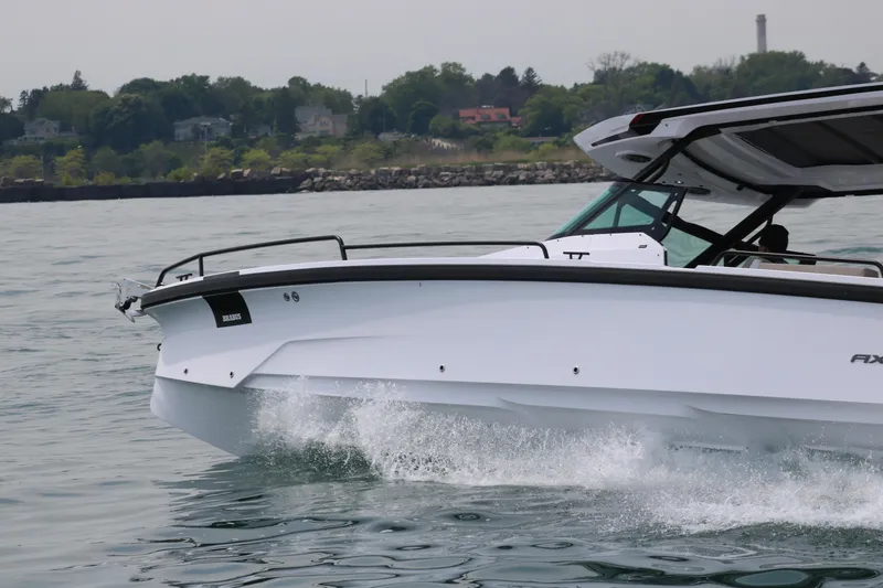 Slide: The Image of 2026 Axopar 29 Sun-Top cruising on water near a scenic shoreline. - 12