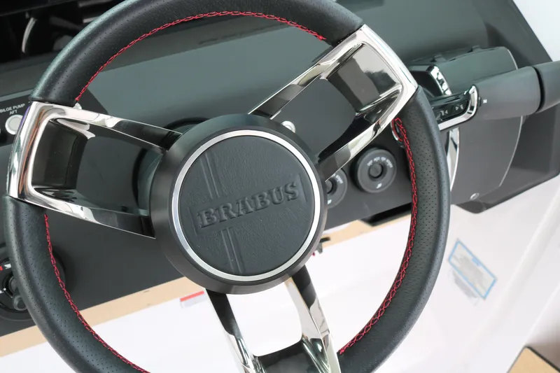 Slide: The Image of Steering wheel of 2026 Axopar 29 Sun-Top boat with Brabus branding and red stitching. - 17