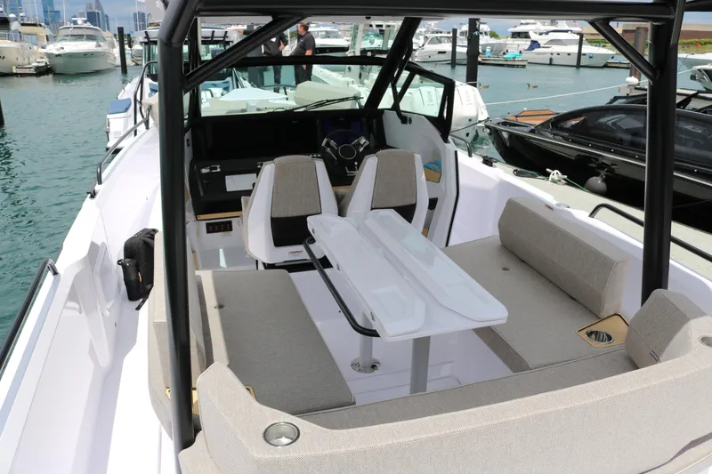 Slide: The Image of 2026 Axopar 29 Sun-Top boat interior with seating and table, docked at marina. - 20