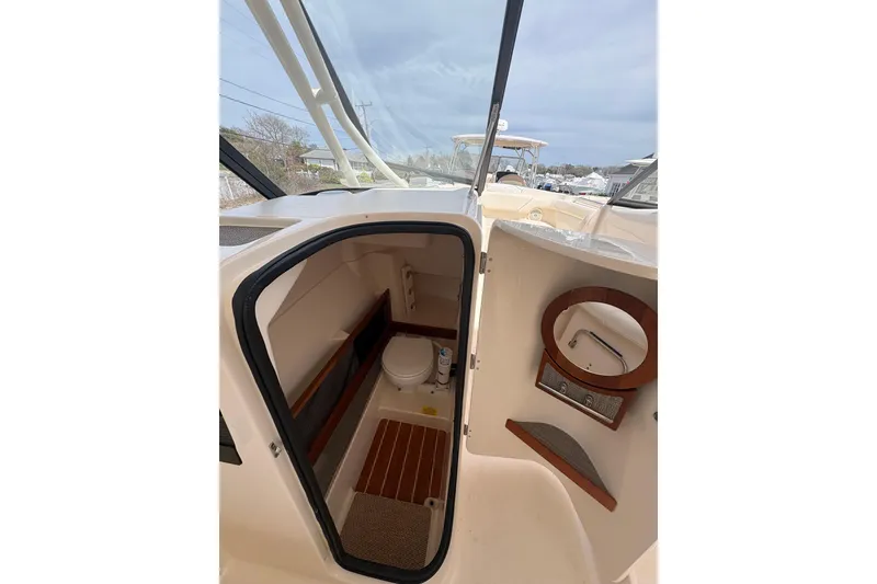 Slide: The Image of 2016 Grady-White Freedom 275 boat interior with compact bathroom and wooden accents. - 11