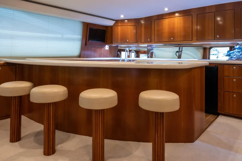 Slide: The Image of Luxurious 2001 Donzi yacht interior with elegant bar and stools, featuring wooden cabinetry and modern lighting. - 26