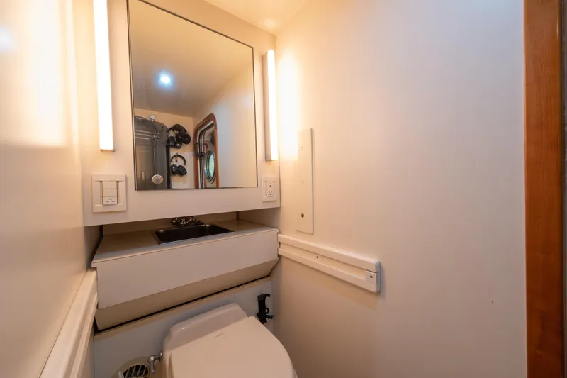 Slide: The Image of Compact bathroom in a 2001 Donzi boat, featuring a mirror, sink, and toilet. - 53